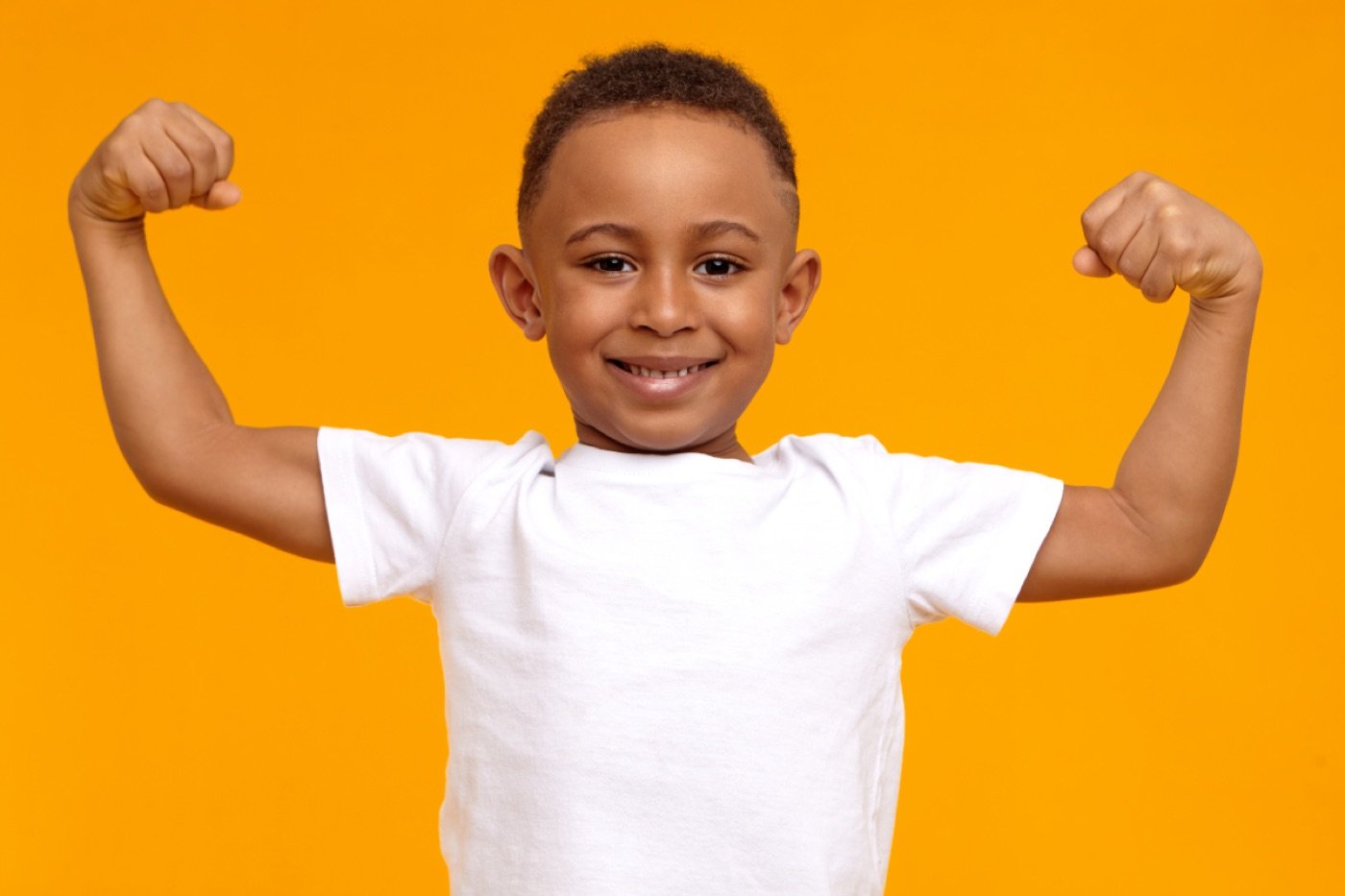 Confident young boy flexing his arms and smiling