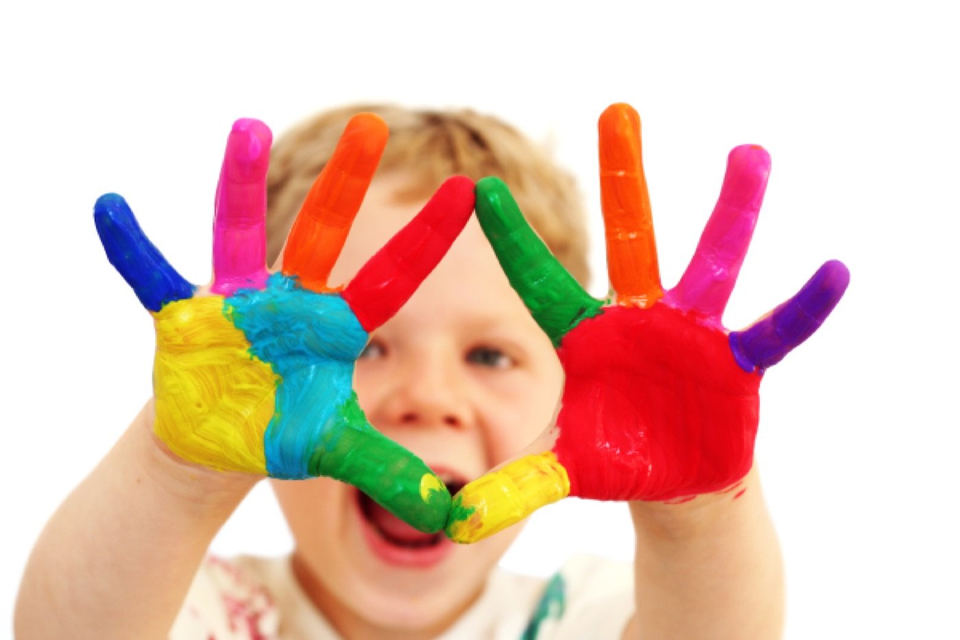 Smiling child holding up hands covered in colorful paint