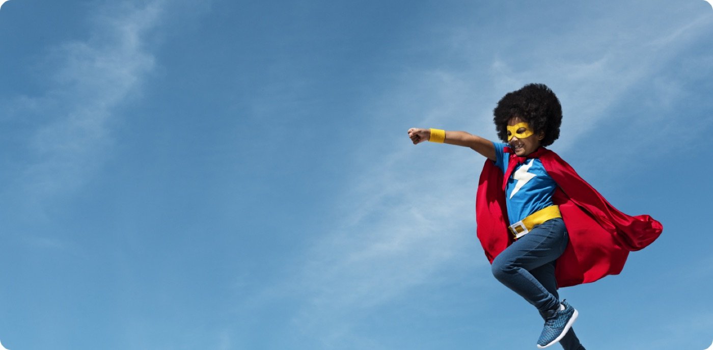 Child in a superhero cape leaping into the sky