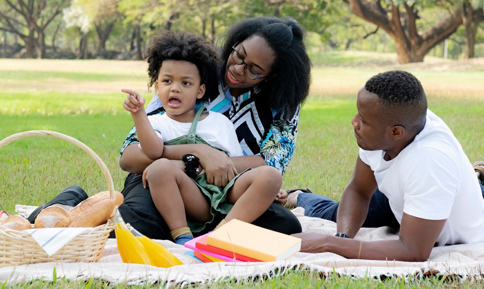Parents and their young son enjoying a picnic with books in the park