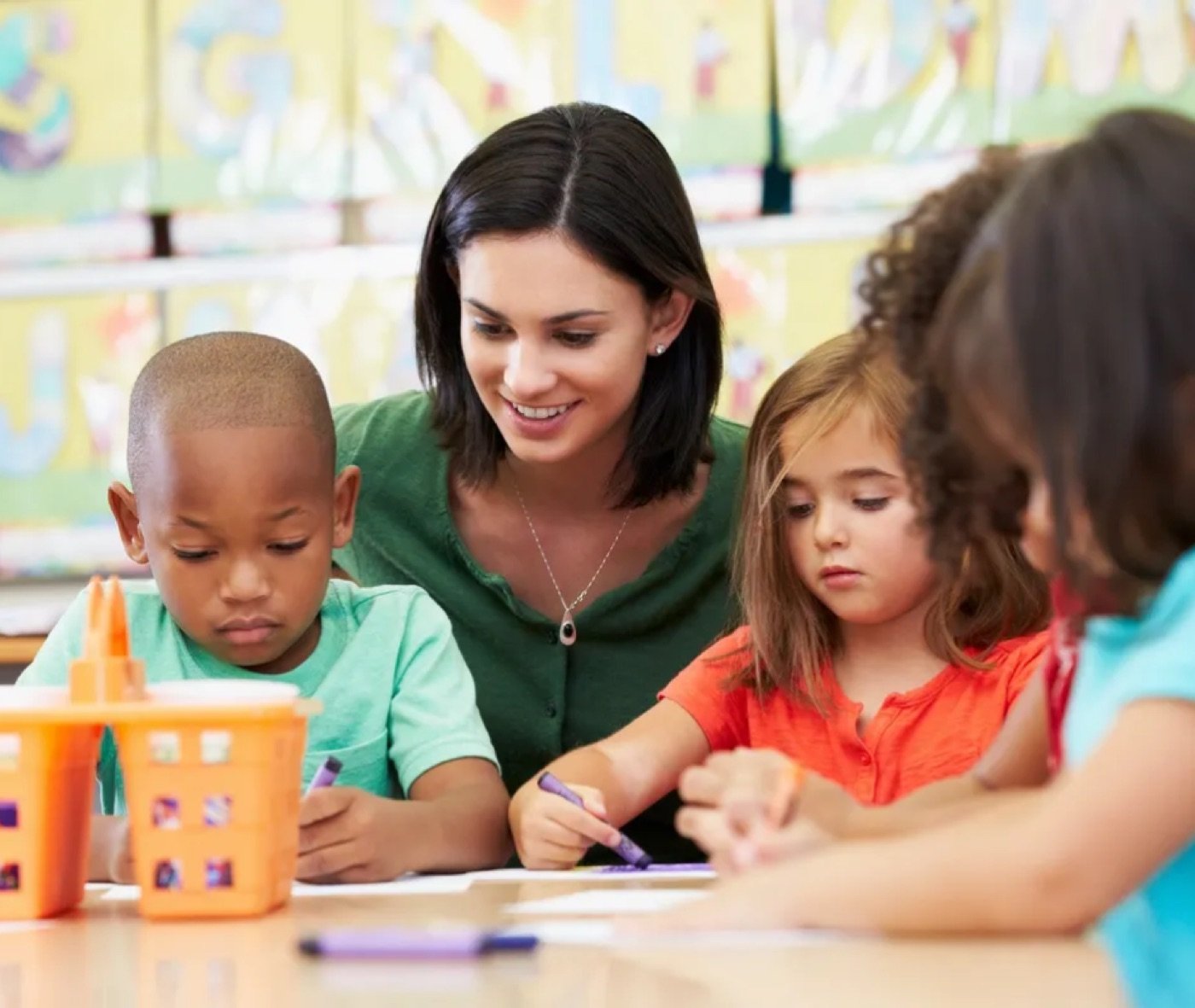 Teacher working with young students at a table