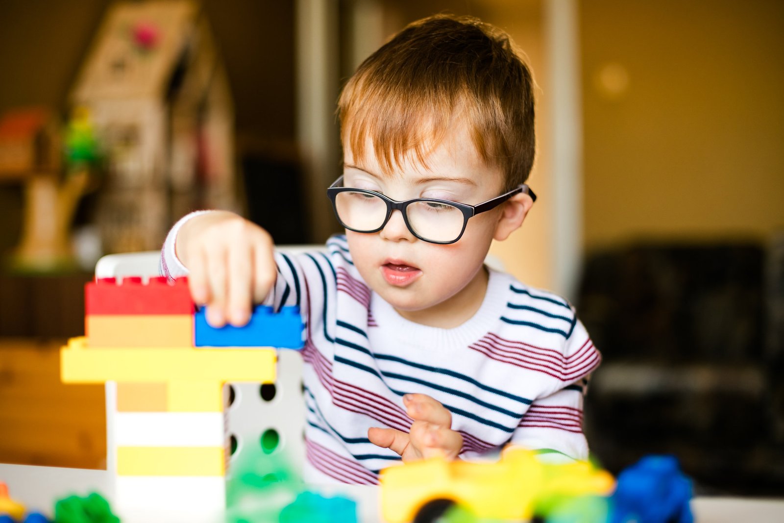Young boy with glasses building a tower with colorful toy blocks