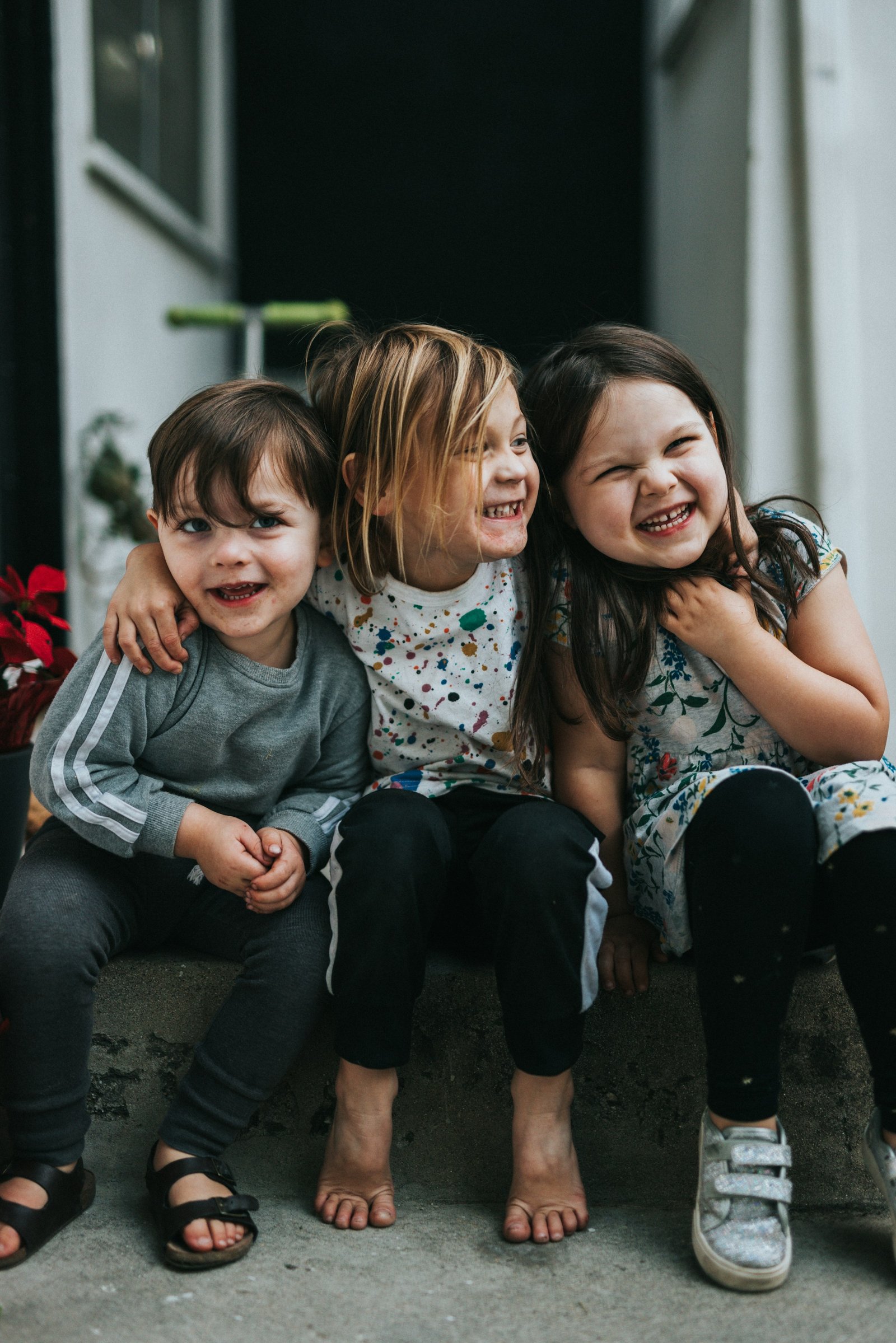 Three young children laughing and hugging each other